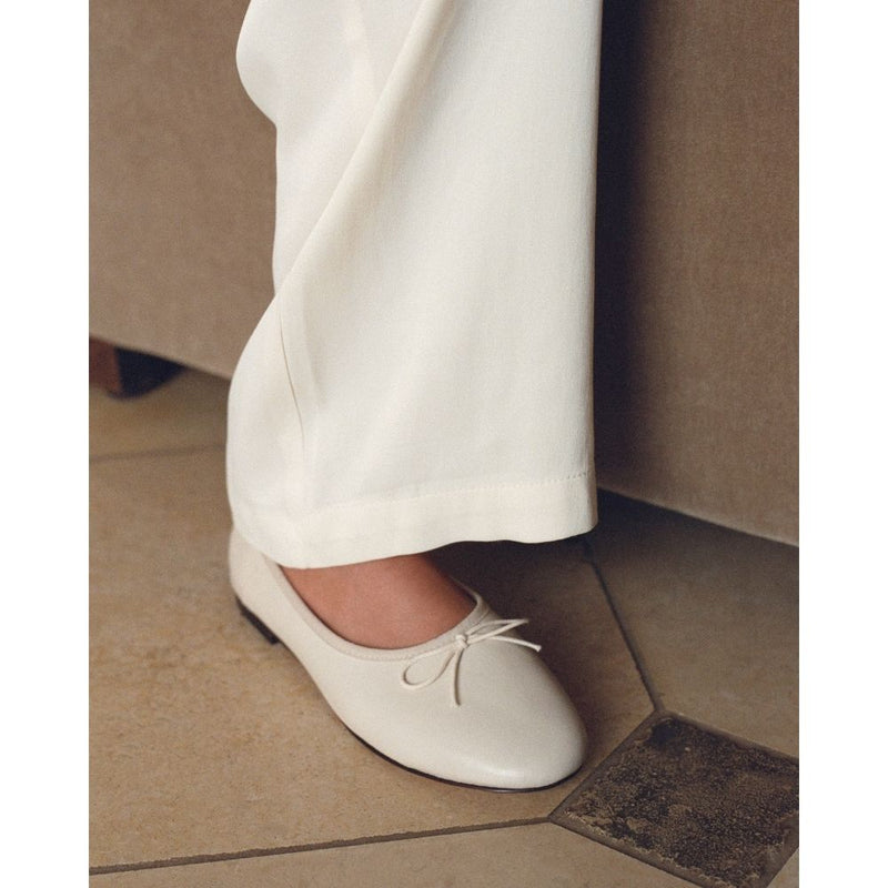 Ivory leather ballet flats with a classic round-toe silhouette, delicate bow detail, and padded leather insole. A timeless essential for effortless everyday elegance.