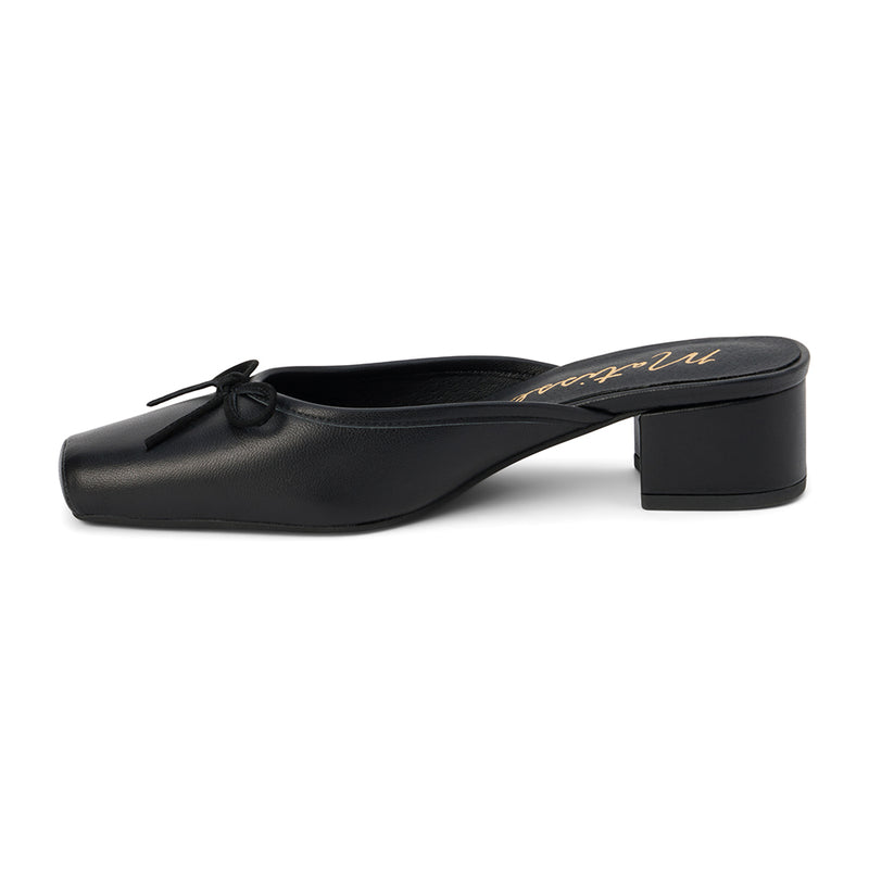 Elegant black mule heels with a square toe and small bow detail, featuring a comfortable block heel for versatile day-to-night wear.