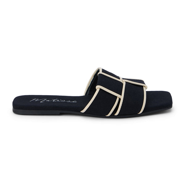 Flat slide sandals in black, featuring crisscrossed cream straps. The sandals have a square toe and a minimalist design, perfect for casual yet stylish wear.