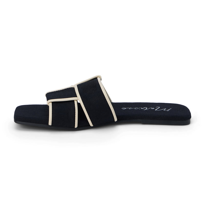 Flat slide sandals in black, featuring crisscrossed cream straps. The sandals have a square toe and a minimalist design, perfect for casual yet stylish wear.