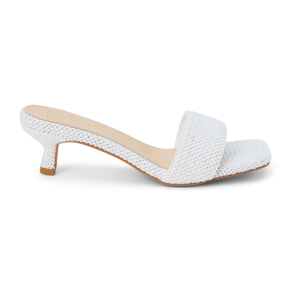 A modern take on a classic silhouette, these white woven kitten heel mules feature a textured raffia design with a square toe and a comfortable low heel. Effortlessly chic for warm-weather styling.