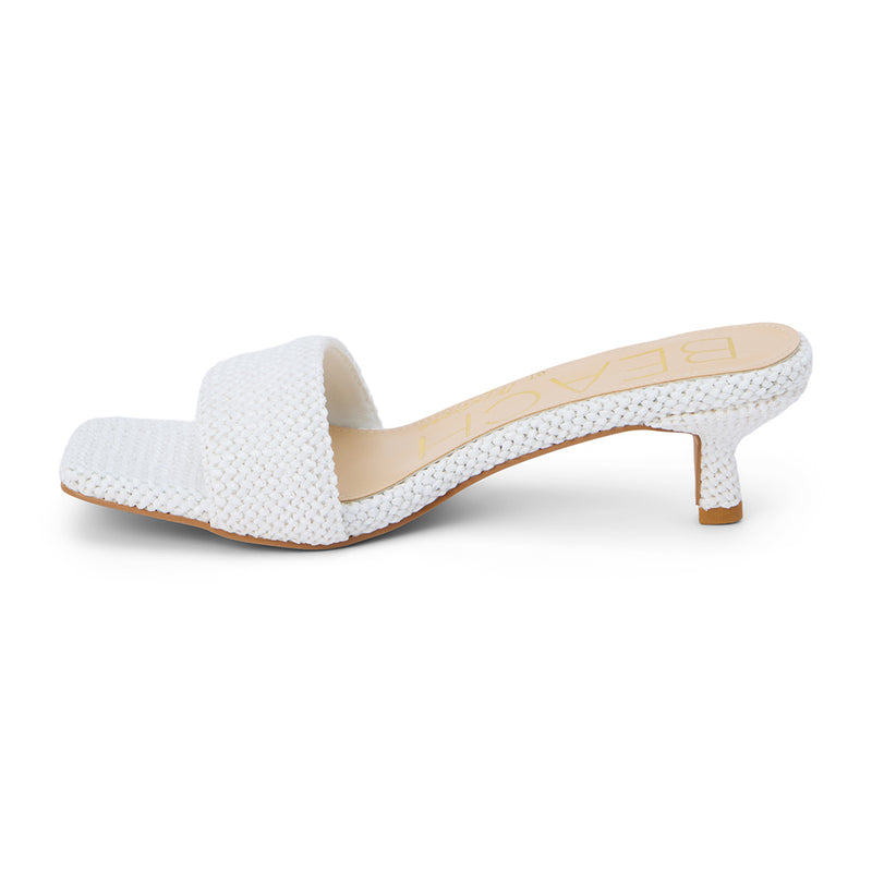 A modern take on a classic silhouette, these white woven kitten heel mules feature a textured raffia design with a square toe and a comfortable low heel. Effortlessly chic for warm-weather styling.