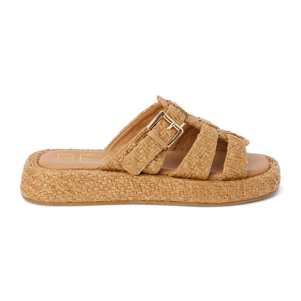 Tan raffia platform slide sandals with woven straps and an adjustable buckle detail. A breezy, laid-back style perfect for warm-weather wear.