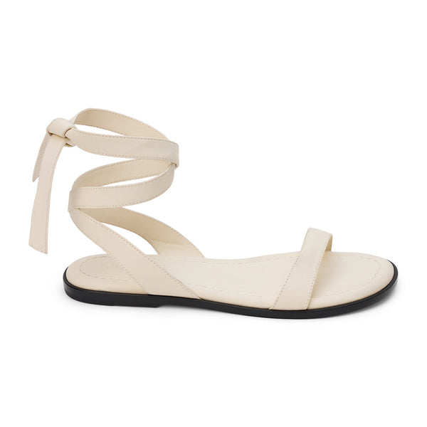 Ivory leather flat sandal with delicate straps and a secure ankle tie. A minimalist and feminine silhouette, perfect for effortless warm-weather styling.