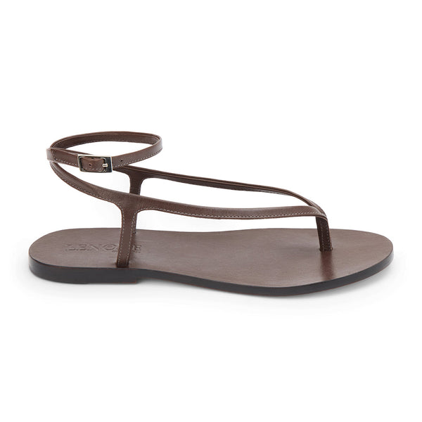 Dark brown leather thong sandal with a minimalist strappy design and adjustable ankle buckle. A sleek and versatile style for effortless warm-weather dressing.