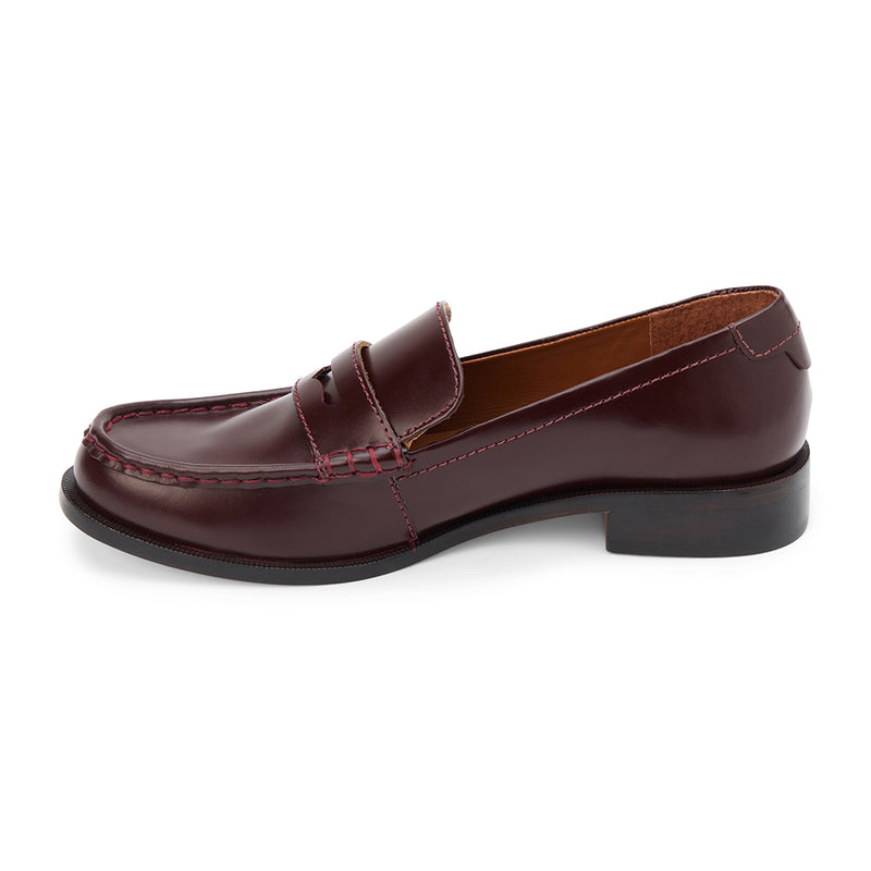 Burgundy leather penny loafers with a polished finish, classic moccasin stitching, and a low stacked heel. A timeless staple for effortless sophistication.